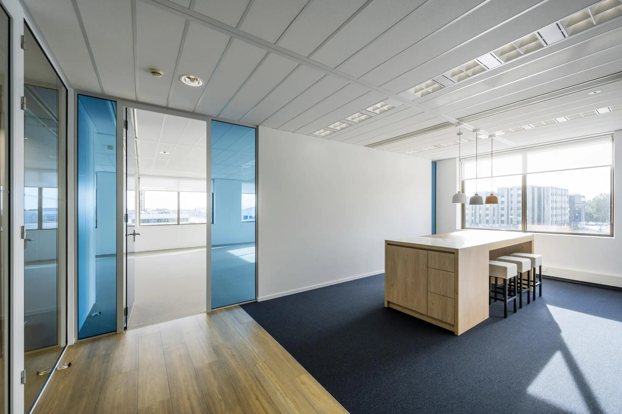 Moderne, lichte kantoorruimte aan het Airportplein in Rotterdam met glazen wanden en een grote houten vergadertafel.